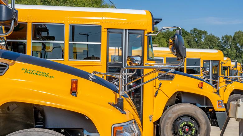 Yellow electric school bus plugged in at a charging station.