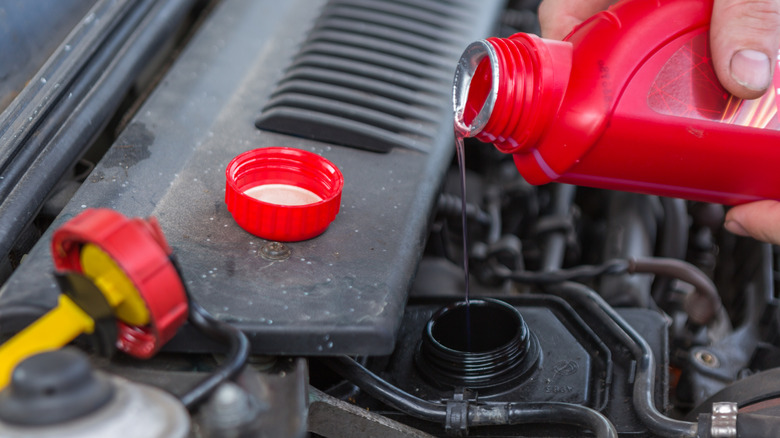 a person pouring power steering fluid into the reservoir